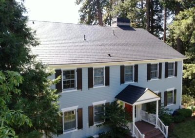 Side view of a composite shingle style metal roof on a traditional style home