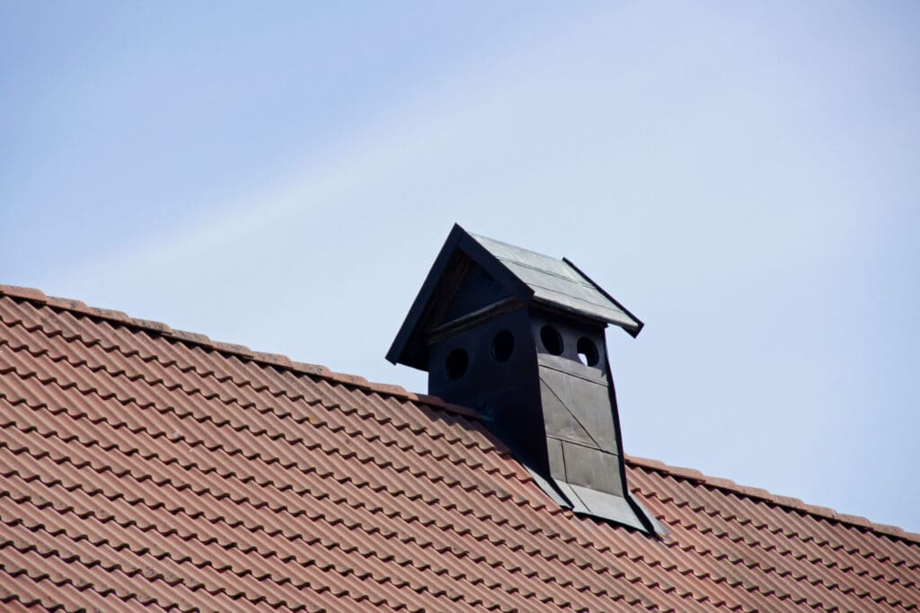 Pipe of ventilation on a roof of tiles to illustrate How Do You Choose The Right Ventilation For Your Roof