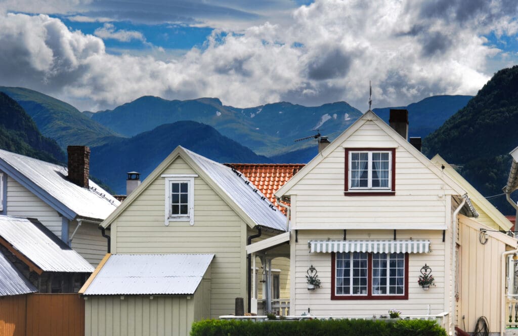 Village of small houses with mountains in the background to illustrate Small Houses With Metal Roofs