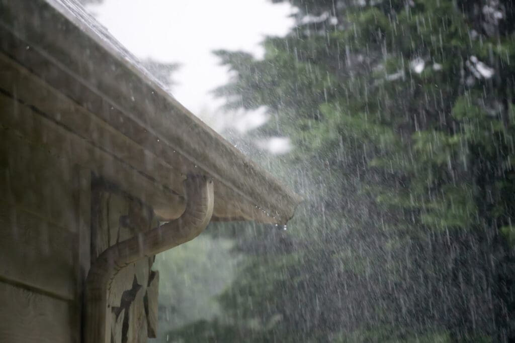 Heavy rain pouring down from passing storm into rain gutters to illustrate How Often to Replace Gutters and best roof for rainy climate