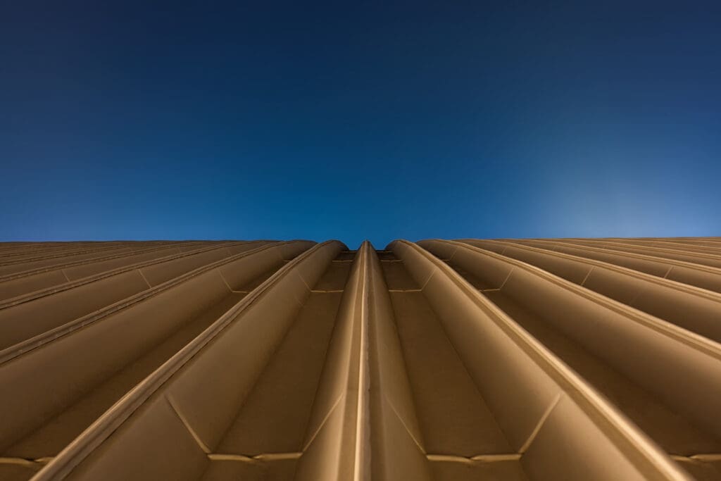 Golden rooftop of a hall with blue sky background to illustrate Stamped Metal Roofing vs. Standing Seam