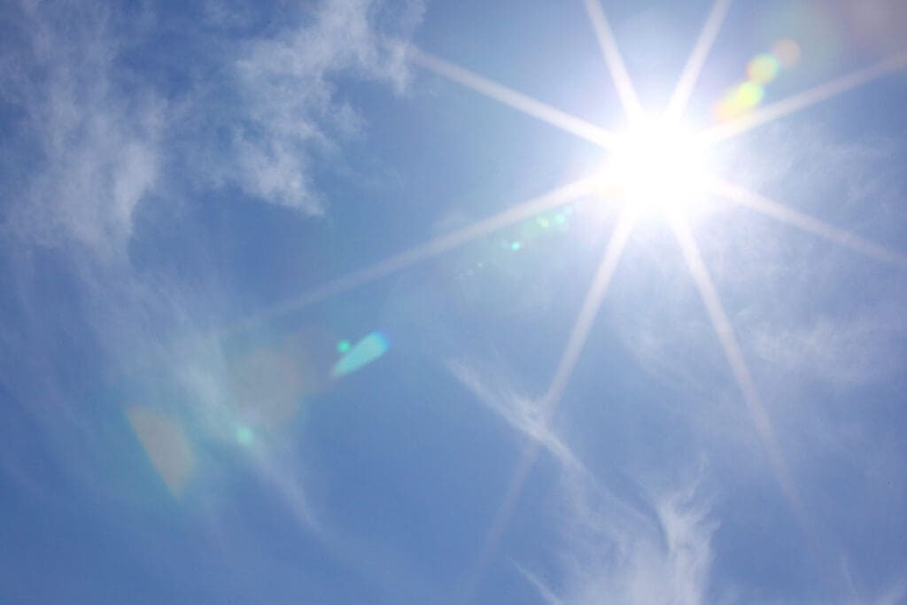 bright sun in blue sky to illustrate how to install solar panels on metal roofing.