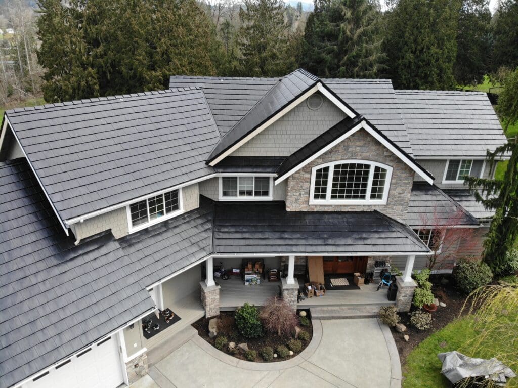 A charcoal gray rustic style metal roof on a large traditional style home